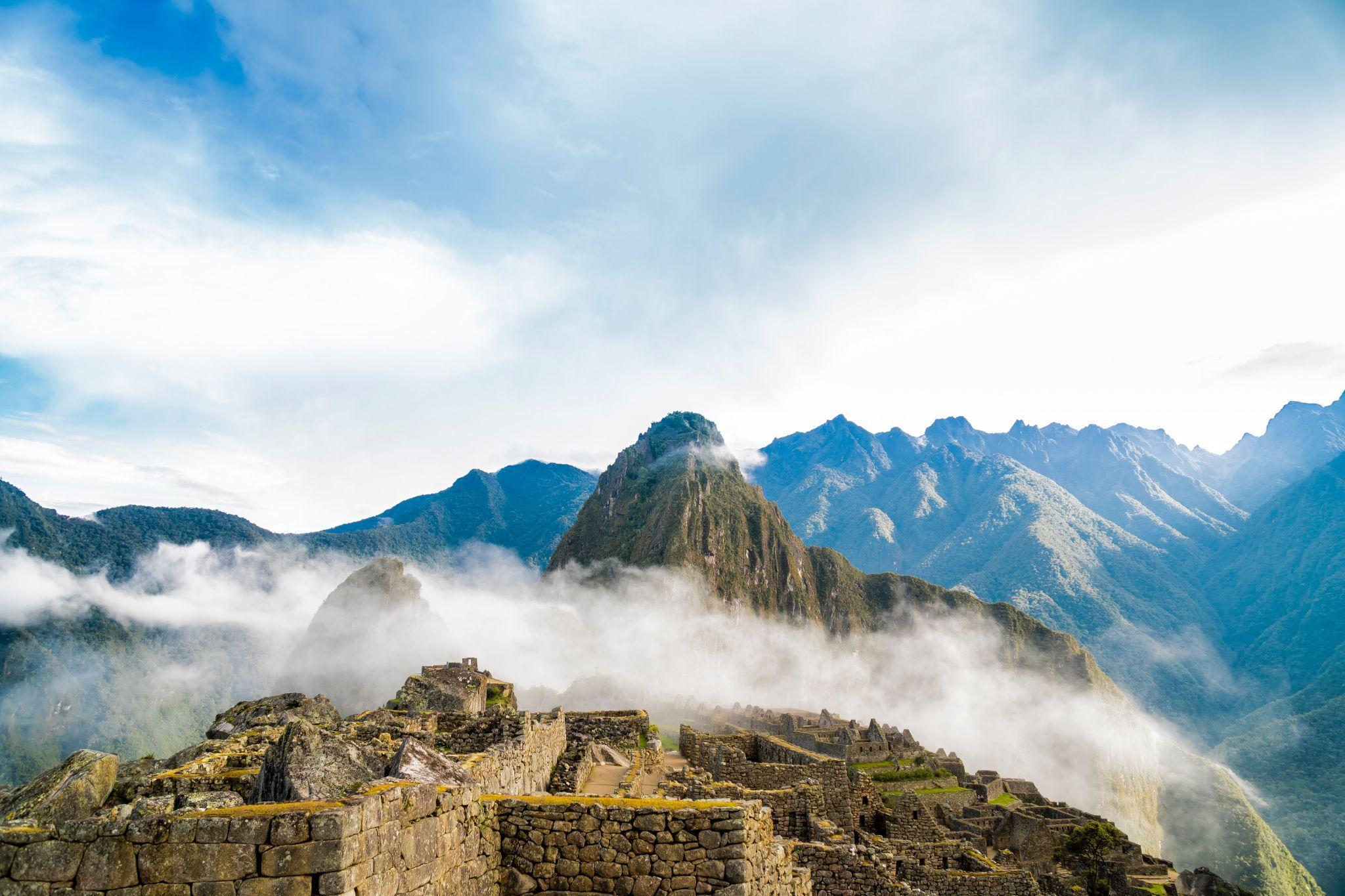 Mountain View of Machu Picchu Image of Mach Picchu shrouded in clouds with mountains in the background.